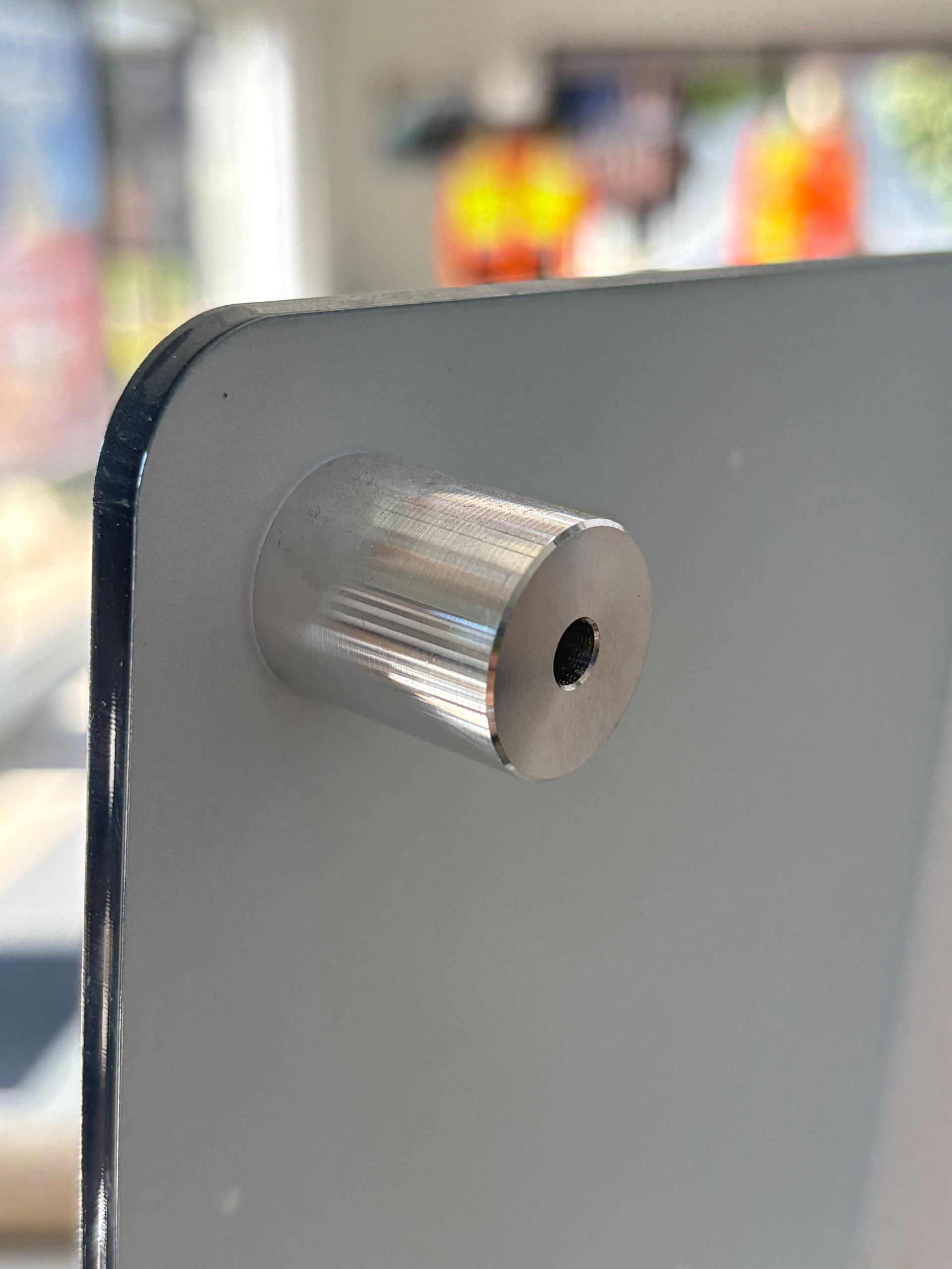 Close-up of a silver knurled metal knob protruding from a gray panel edge.
