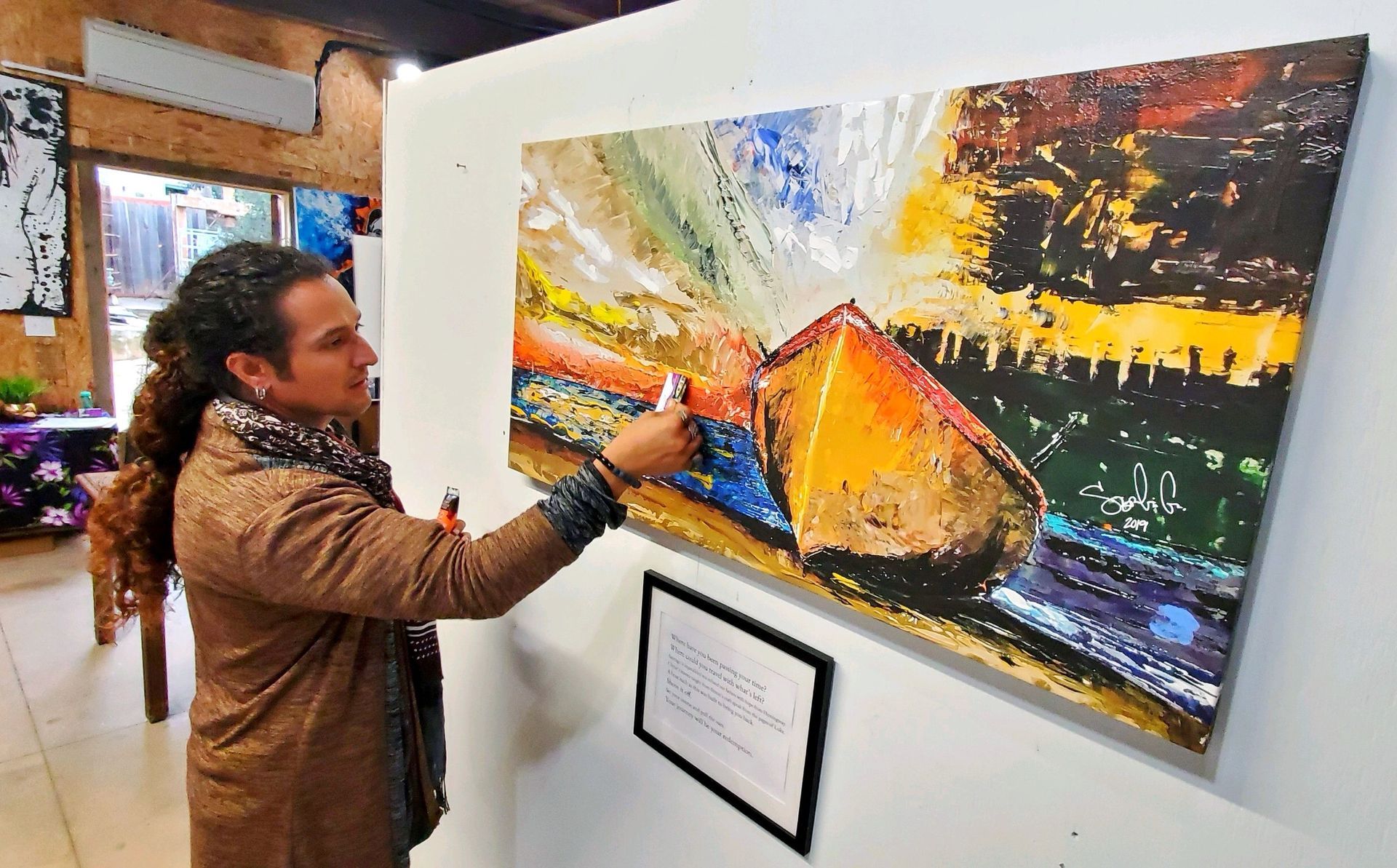 Person painting a colorful abstract canvas in an art gallery interior