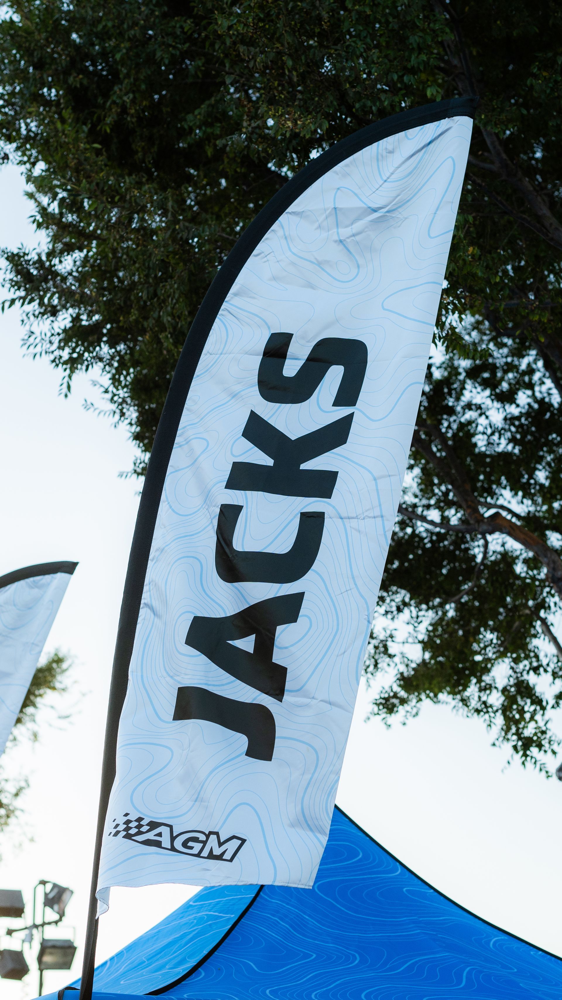 White JACKS flag beside a blue tent under trees outdoors