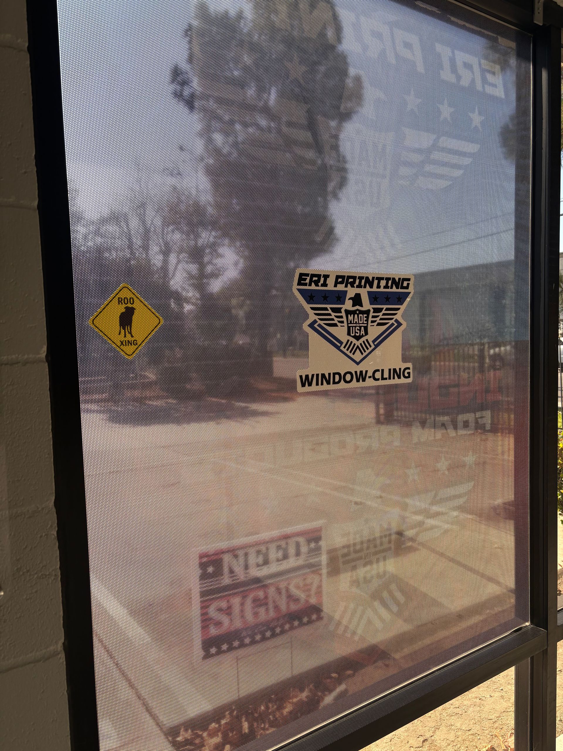 Mesh-covered door with a yellow warning sign and a black logo reading “ERI Printing.”