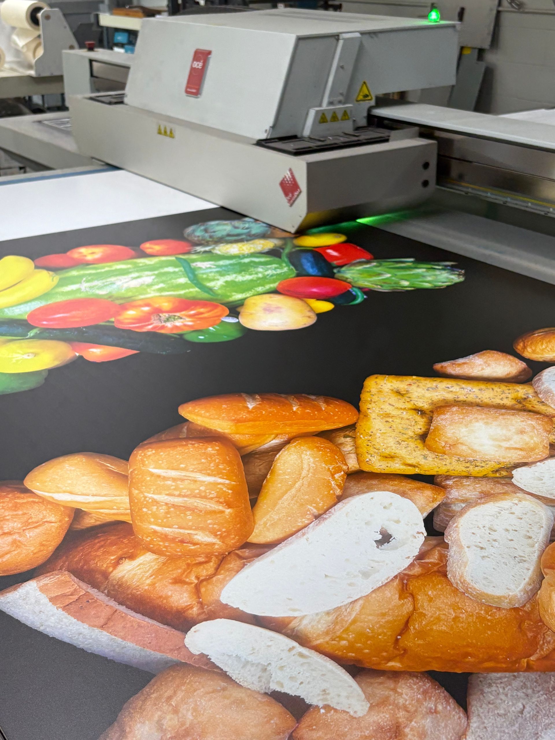 Large-format printer printing colorful fruit and bread images on a black sheet