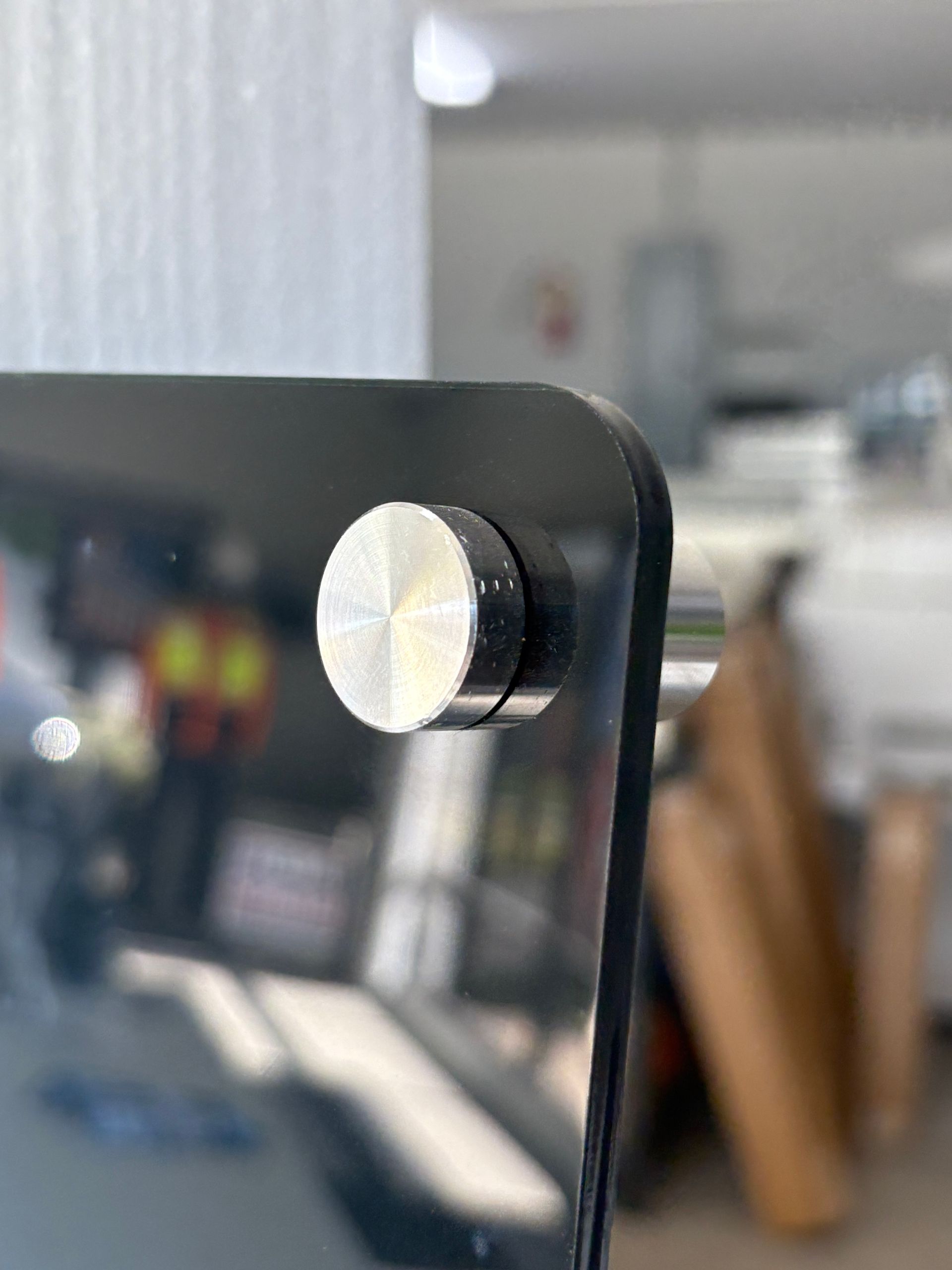 Close-up of a black chair back with a silver adjustment knob in a blurred office setting
