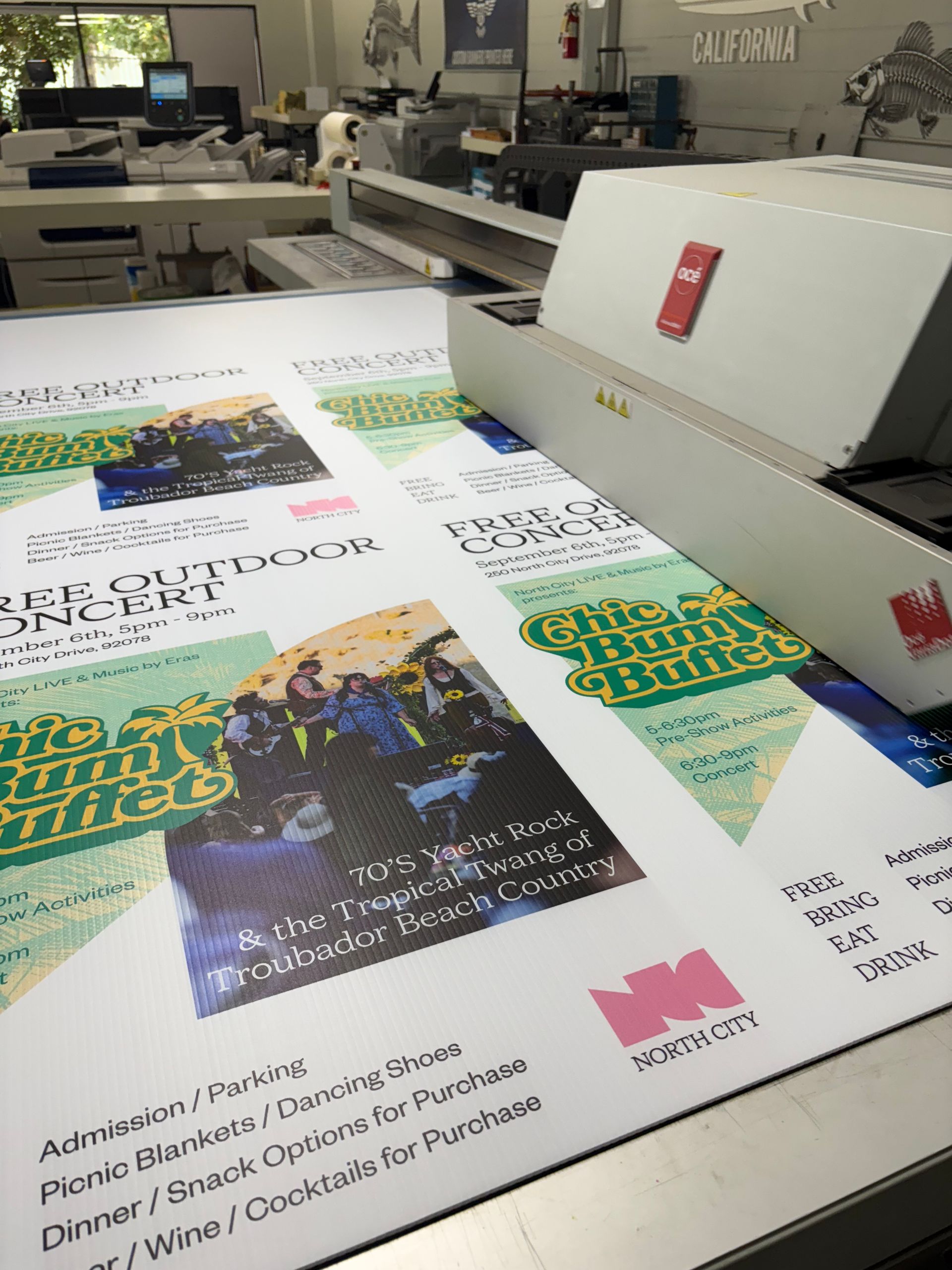 Large printer producing colorful poster sheets in a print shop
