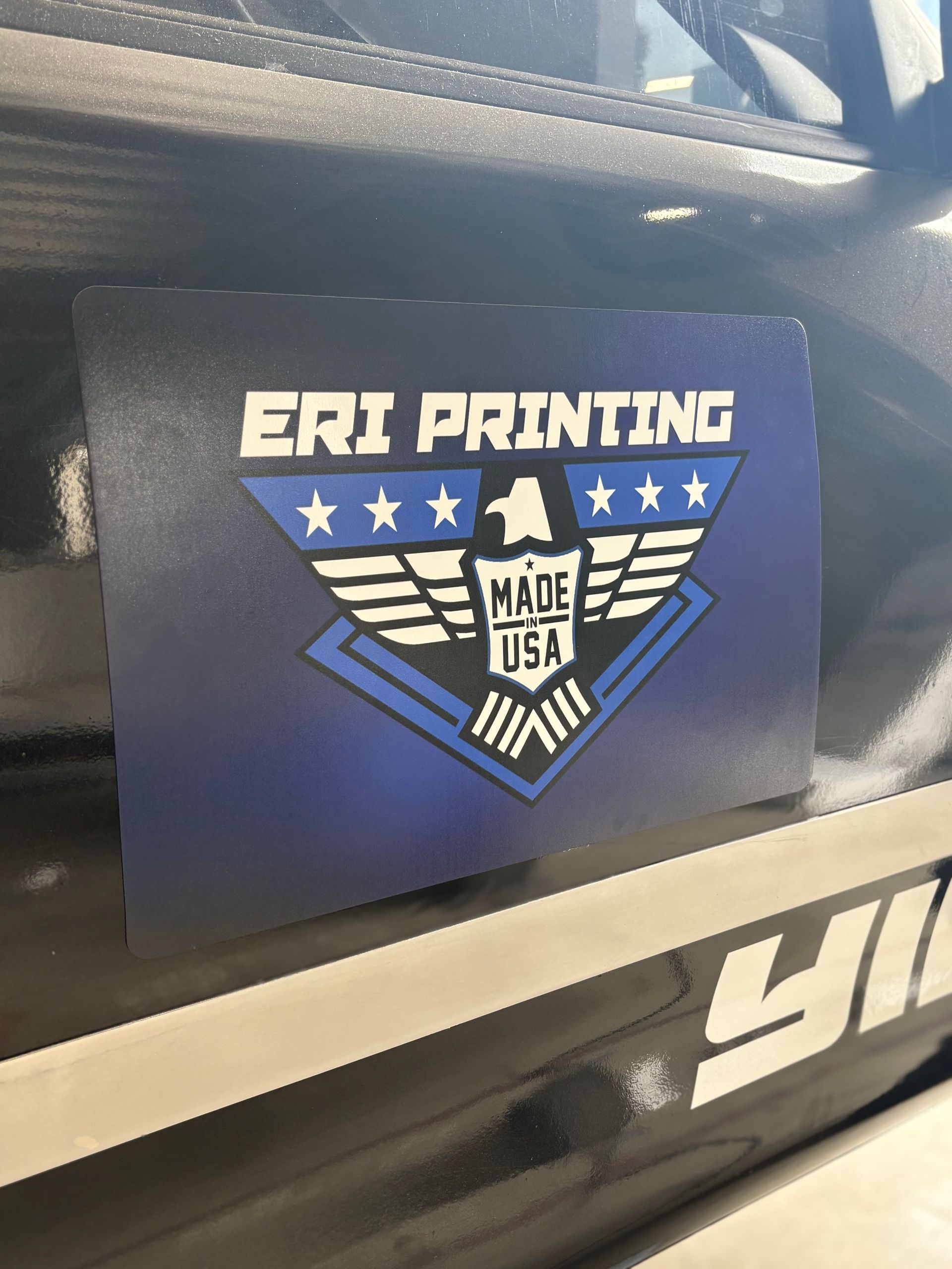 ERI PRINTING logo magnet on a black surface with blue and white winged emblem, Made in USA text