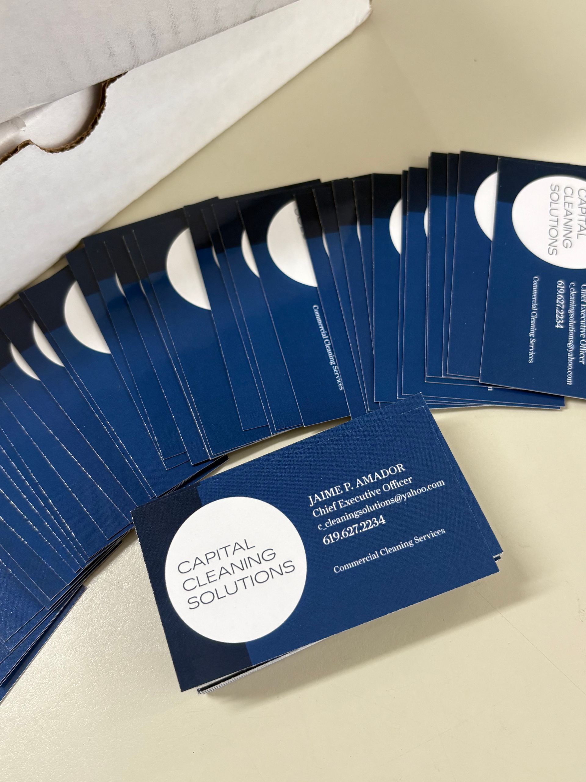 Blue business cards fanned out on a light surface, with one card in front showing a white circle logo.
