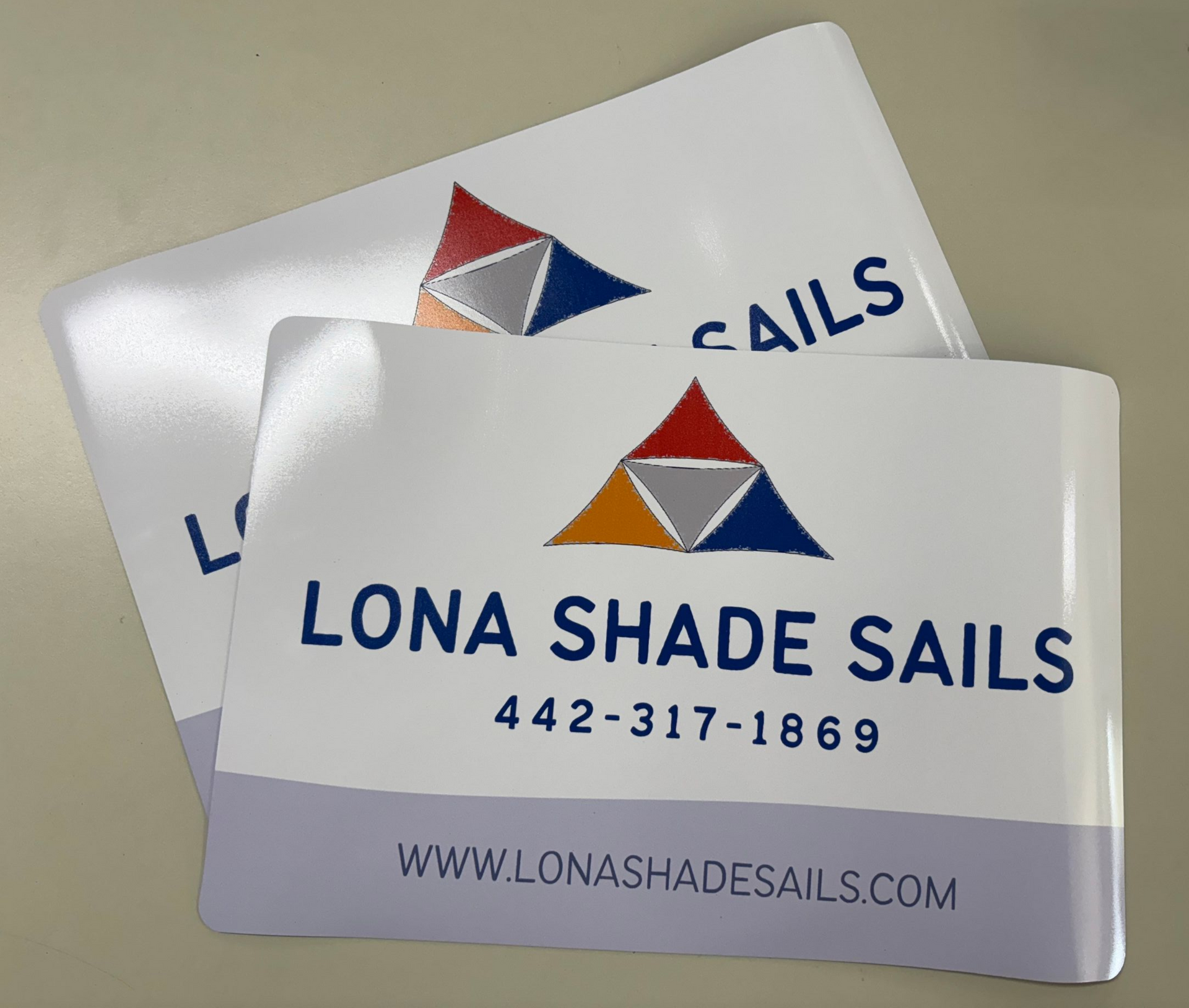 Two Lona Shade Sails magnets, white with blue and multicolor logo and text.
