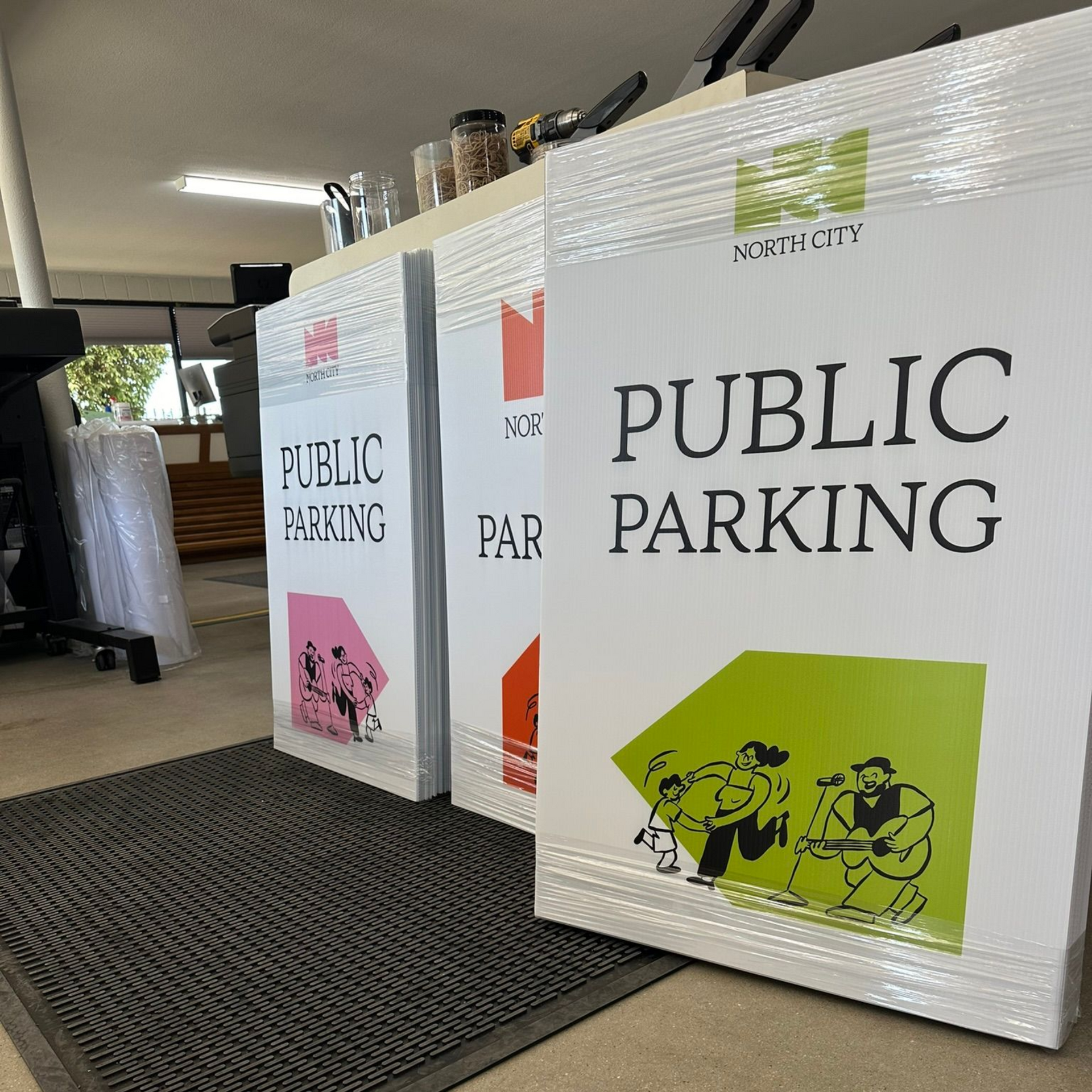 Public parking signs stacked in a lobby, including pink, orange, and green designs.