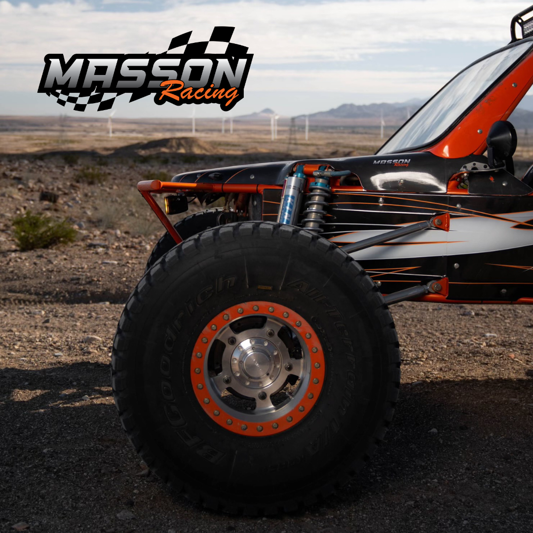 Off-road racing buggy wheel and suspension with Mission Racing logo against a desert backdrop