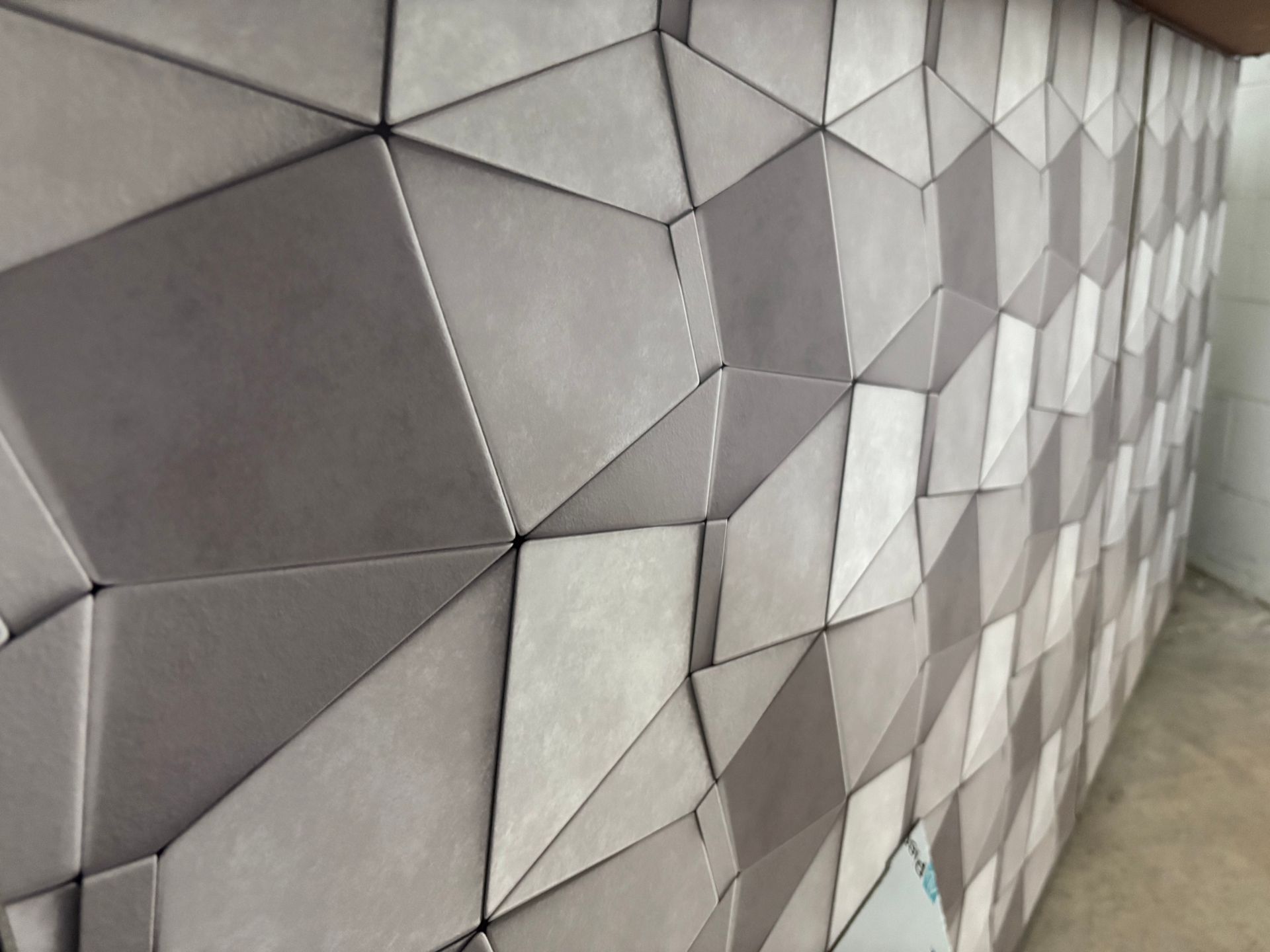 Geometric gray and white tiled wall with faceted 3D pattern