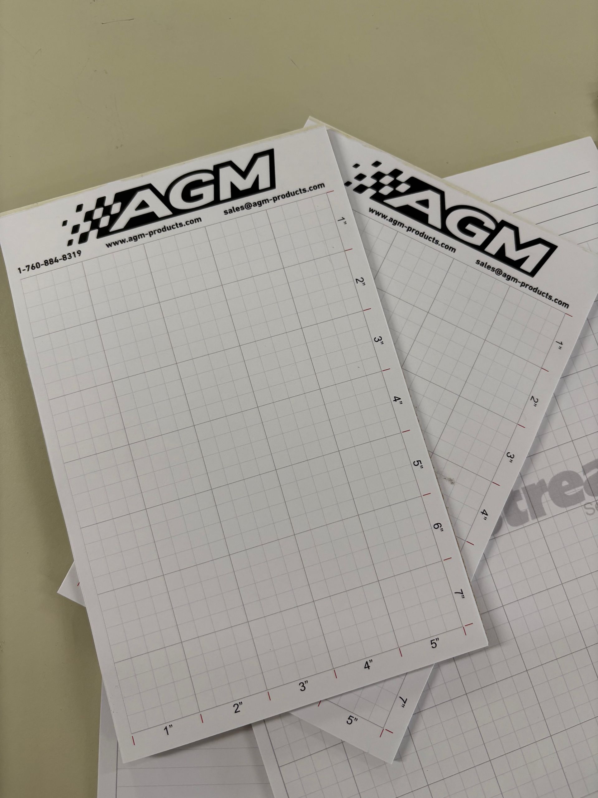 AGM-branded graph paper sheets stacked on a beige surface