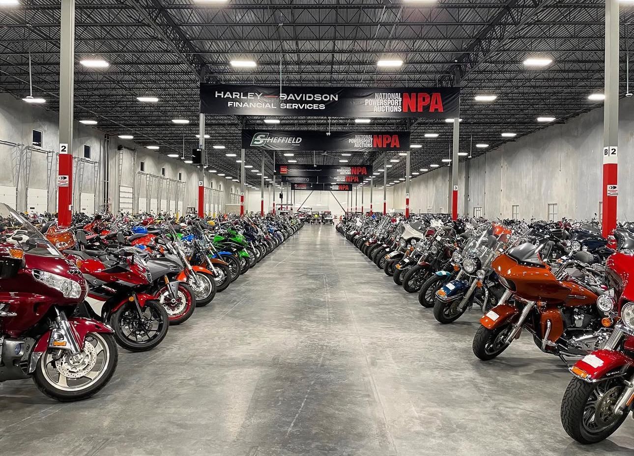Rows of red and black motorcycles in a large showroom with a concrete floor and high ceiling