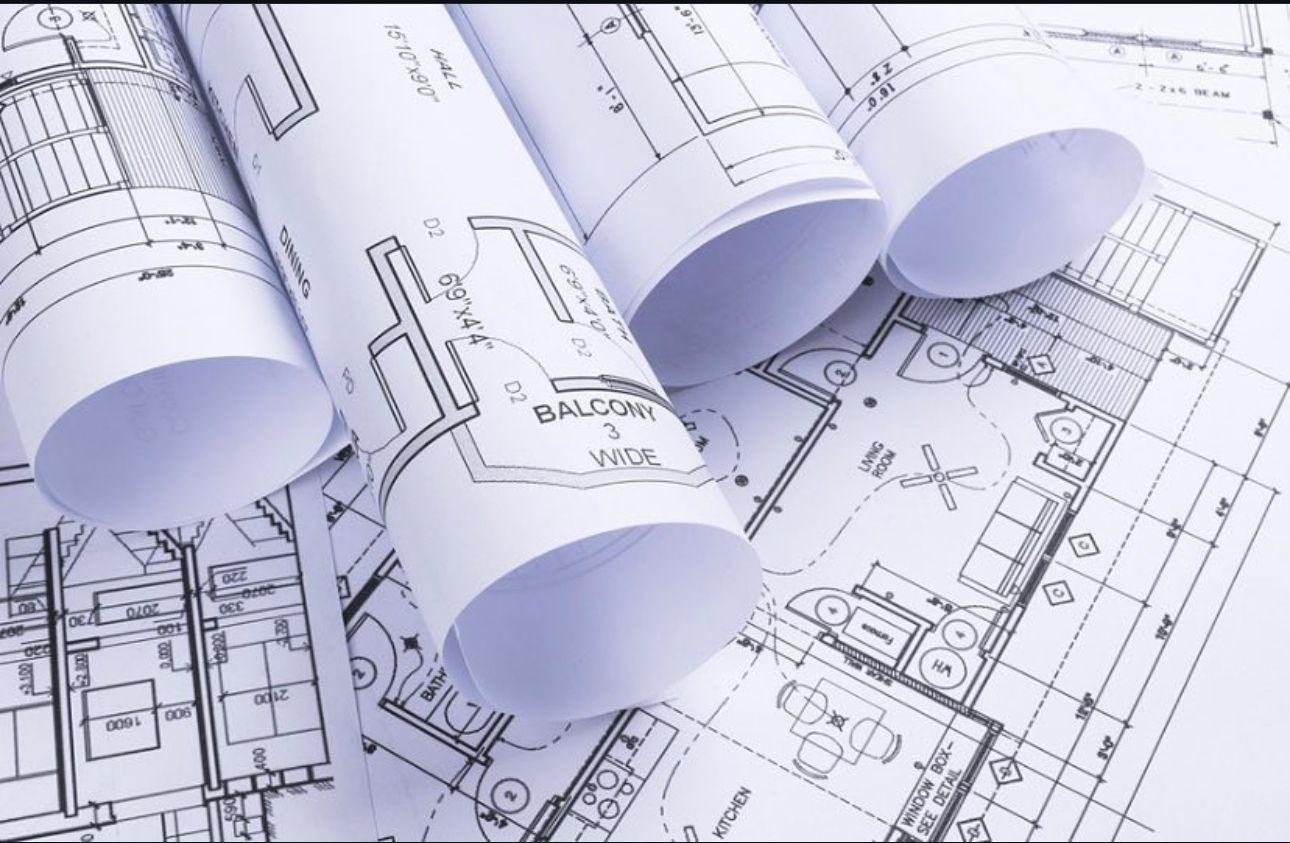 Rolled architectural blueprints spread across a floor plan drawing
