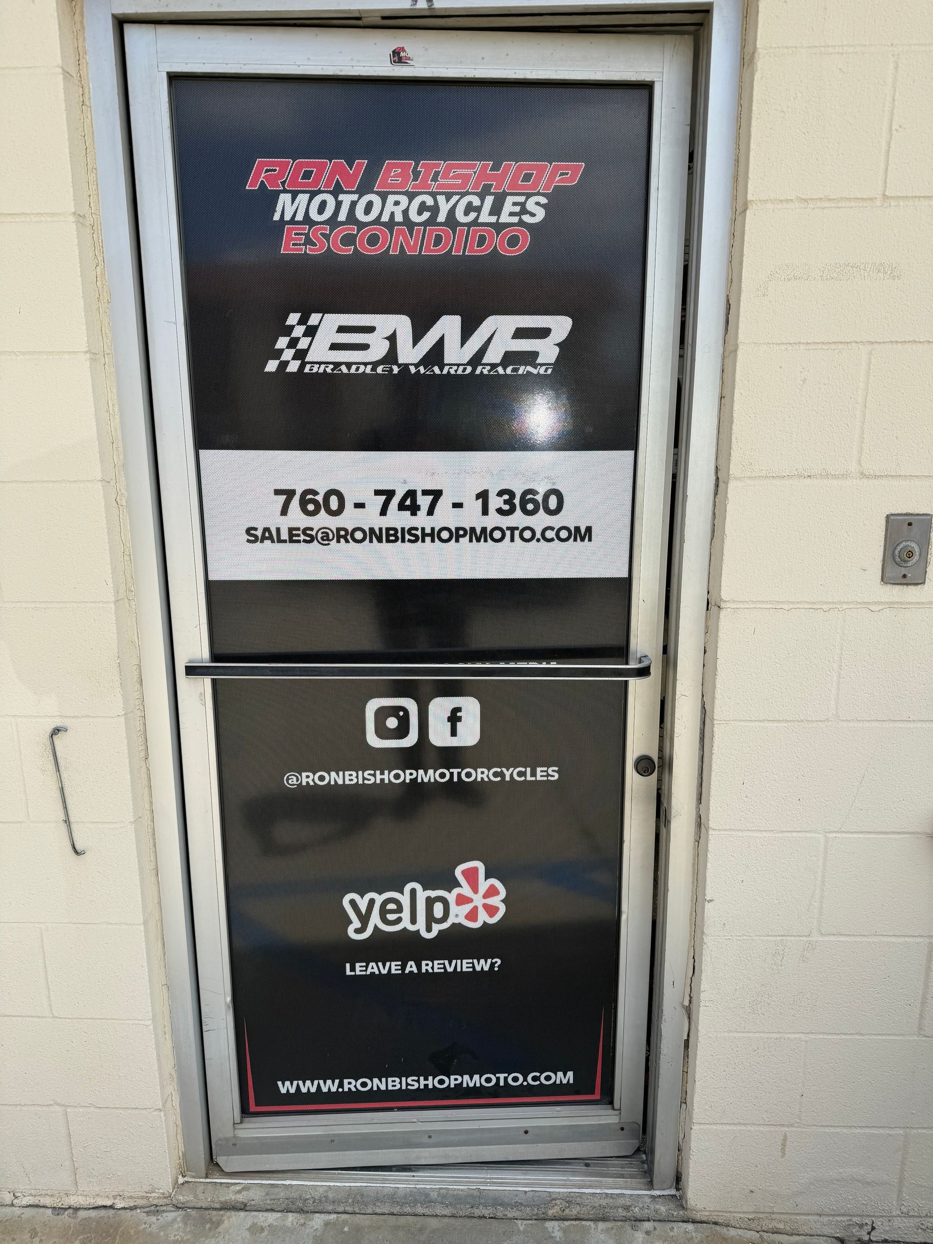 Motorcycle shop door with BWR logo, phone number, social media icons, Yelp logo, and website URL