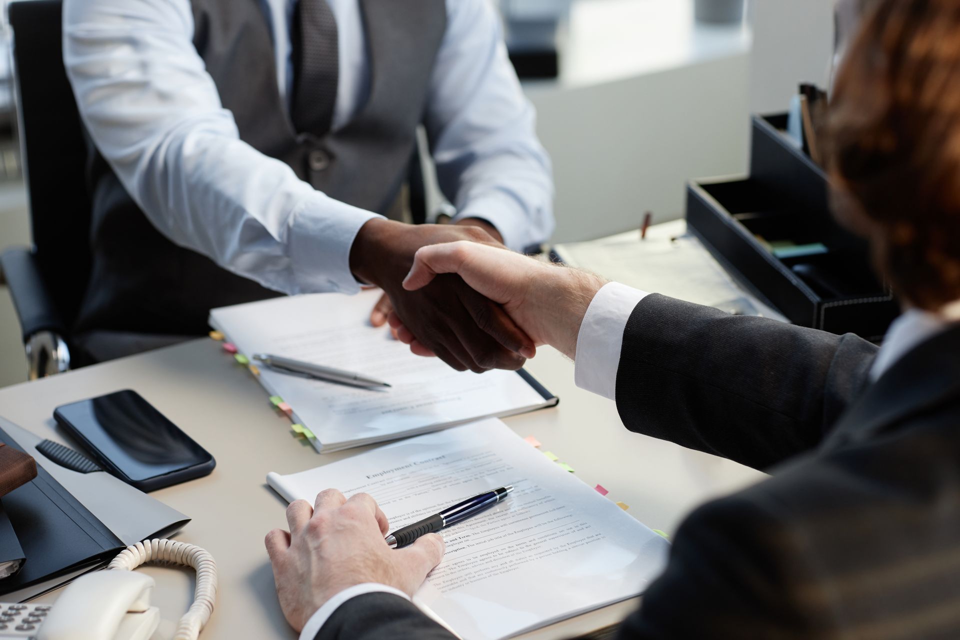 Business handshake over a desk with documents and a notebook in an office setting