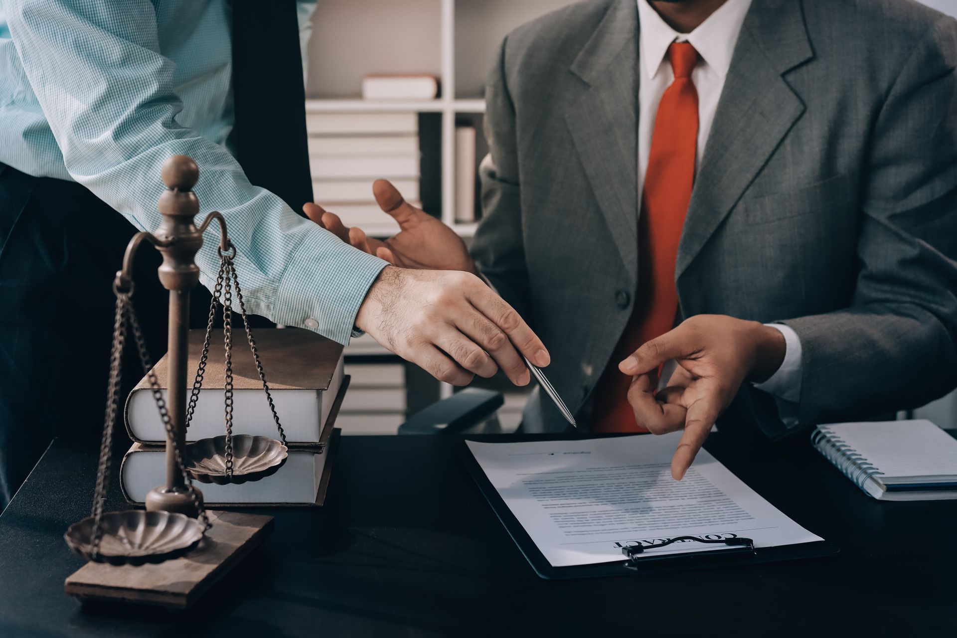 Two professionals reviewing a legal document at a desk with scales of justice and a gavel
