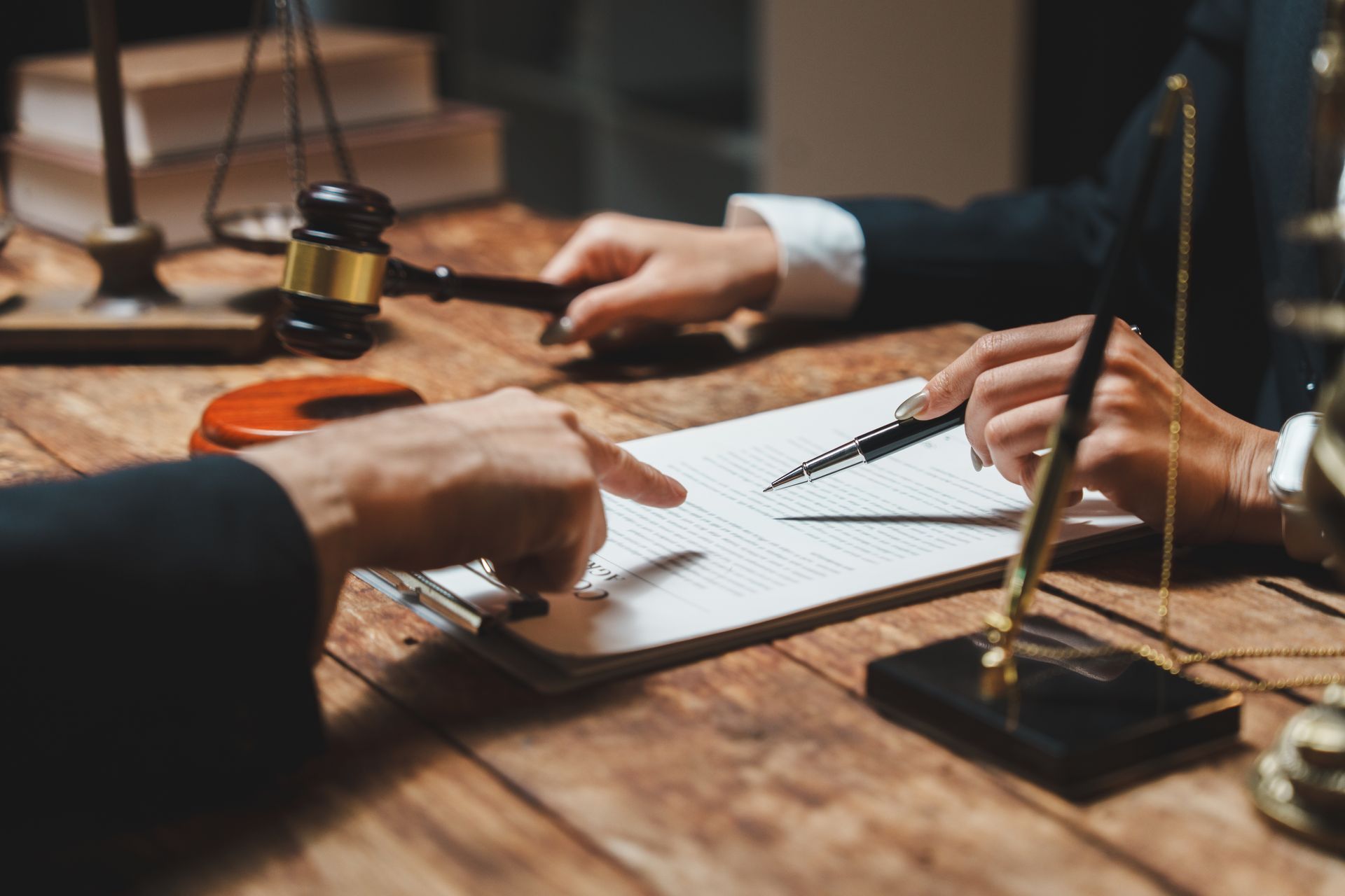 Lawyers in suits reviewing documents at a wooden desk with a gavel and scales of justice