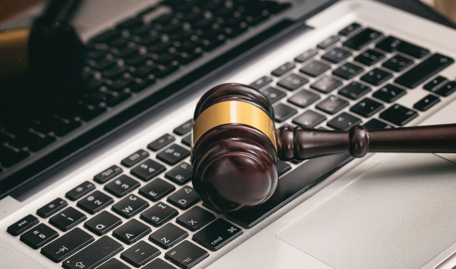 Judge’s gavel resting on a laptop keyboard, symbolizing online legal work or cybersecurity