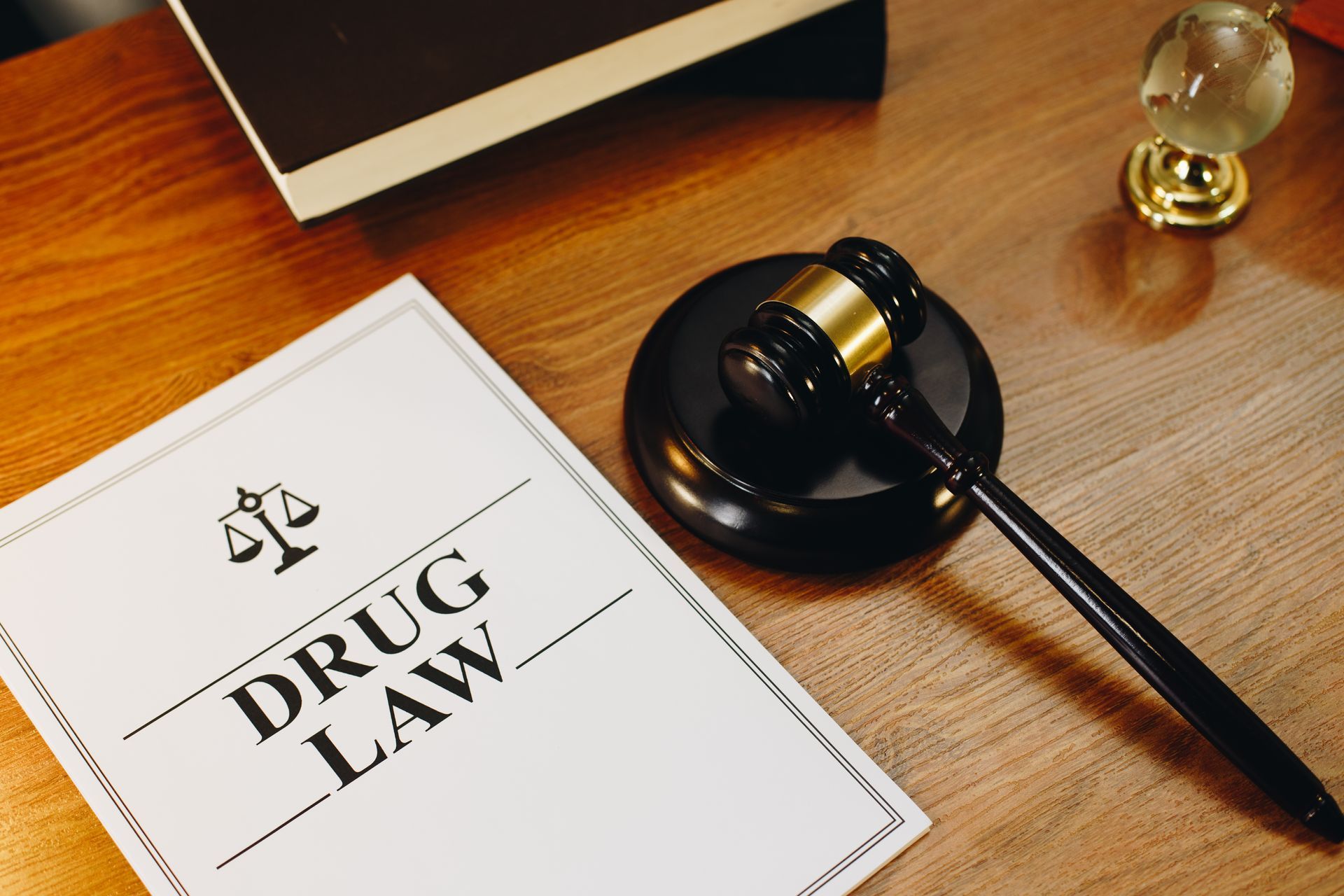 Drug law book on a wooden desk beside a gavel and laptop.