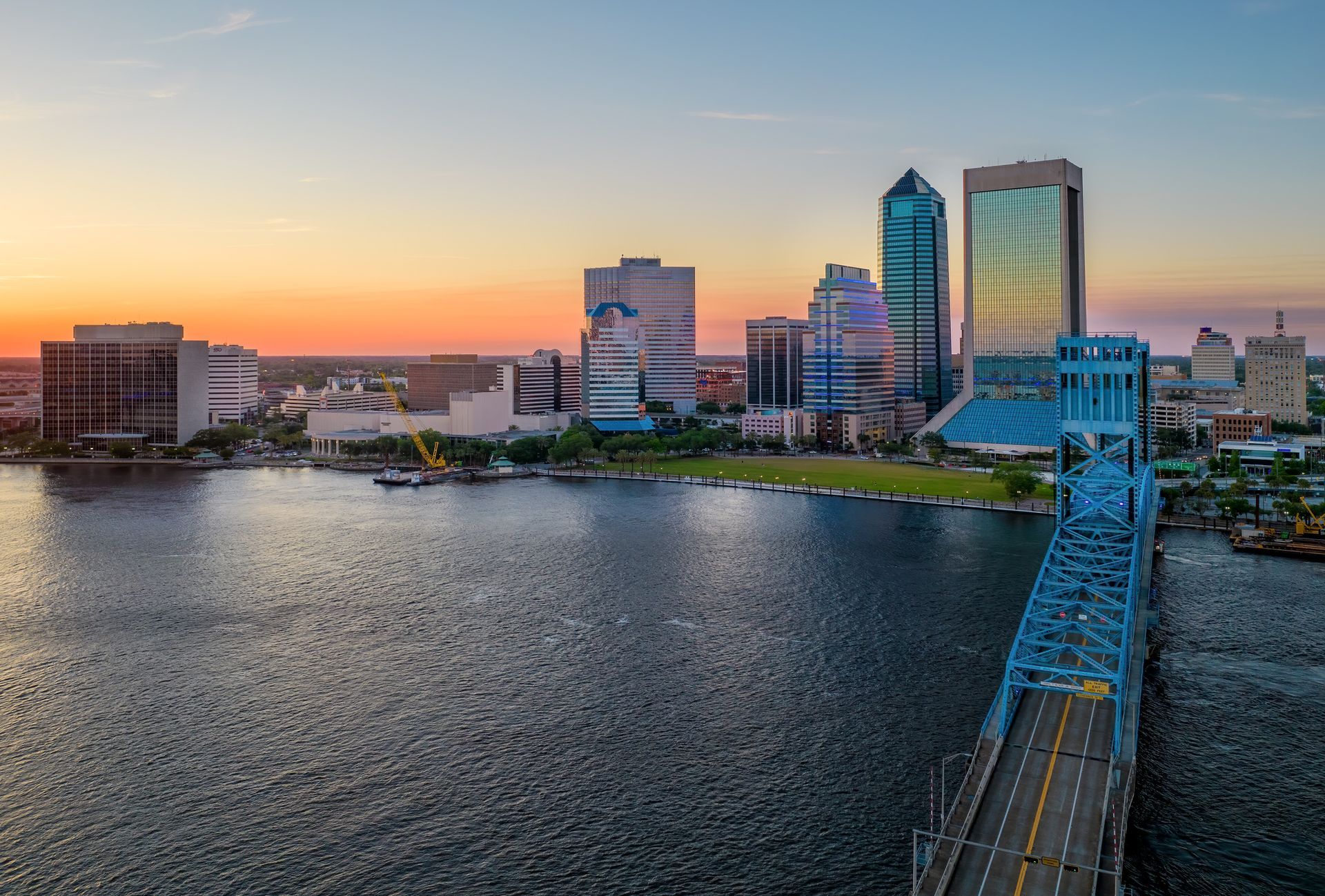 An aerial view of a bridge over a body of water with a city skyline in the background.