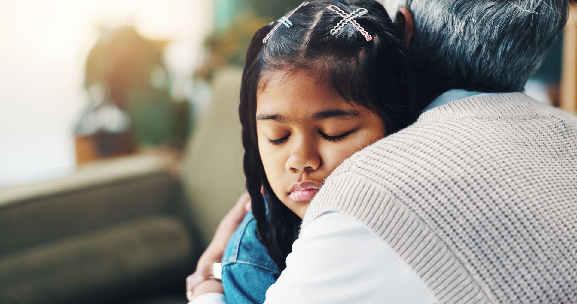A child sleeping while being hugged by an adult on a couch