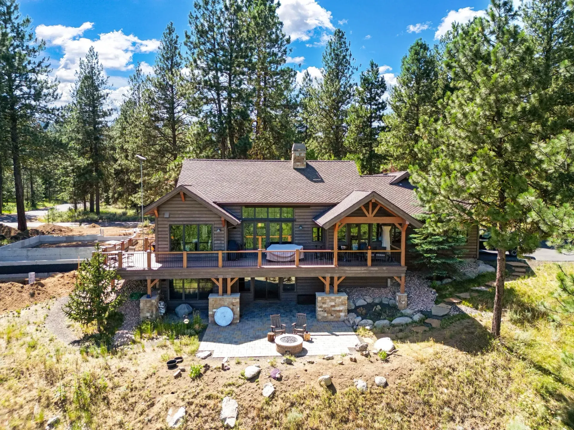 Luxury custom mountain home with steep architectural shingle roof framed by ponderosa pines