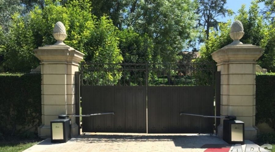 automatic gate security Gastonia NC.jpg: Automated dark metal security driveway gate with stone pillars in Gastonia, NC.