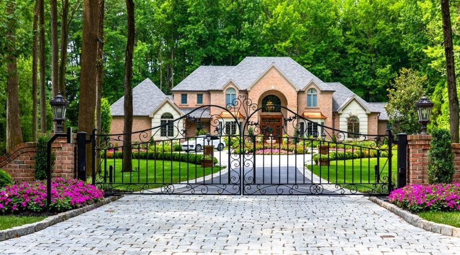 Automated wrought iron driveway gate with ornamental scrollwork in front of a luxury Gastonia, NC ho