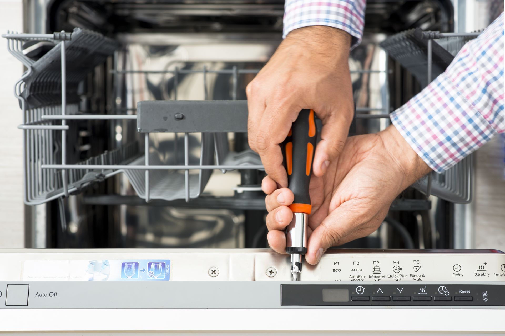 a man is fixing a dishwasher with a screwdriver .