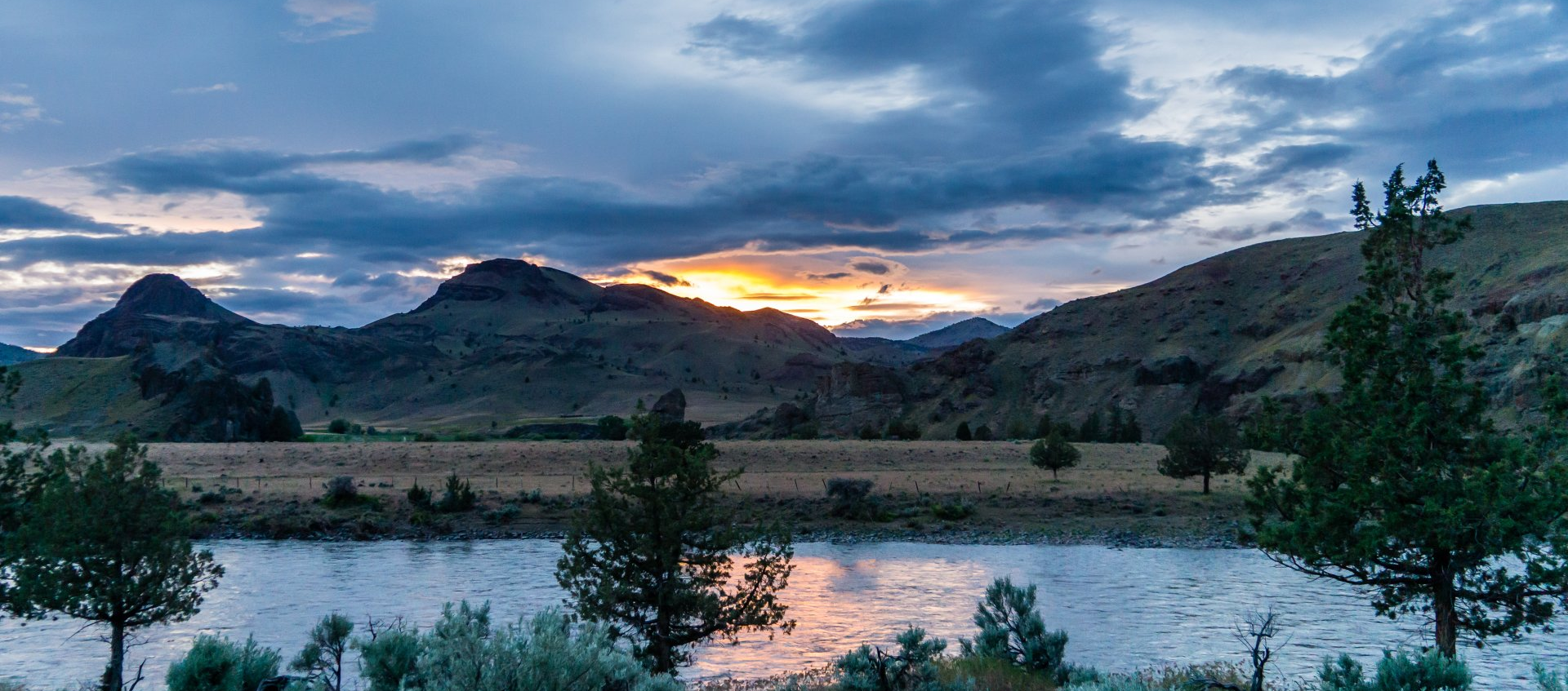 A stunning John Day River sunset over a river with mountains in the background.