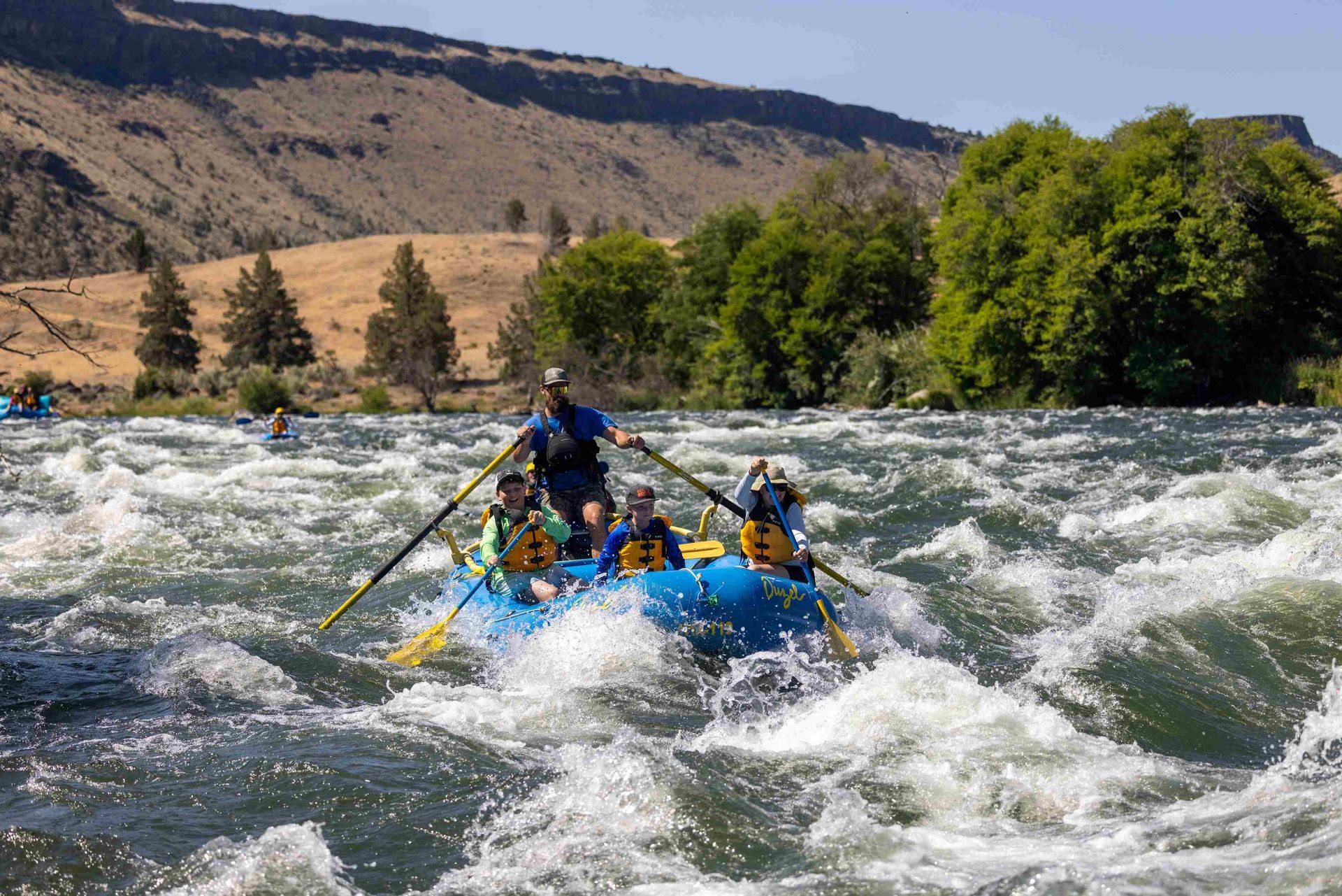 Ouzel guests and guide are rafting down a river.