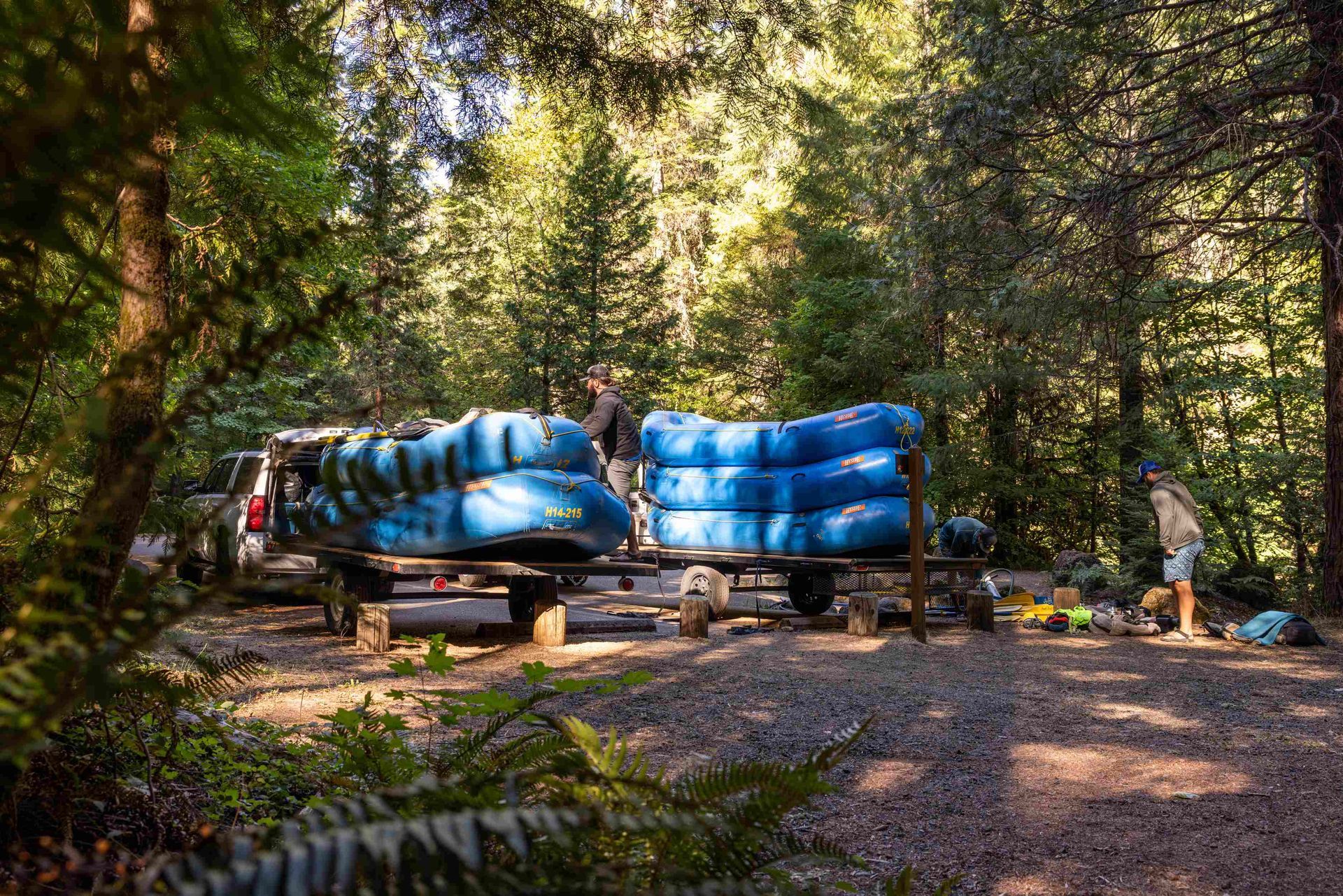 Ouzel guides are unloading rafts from a trailer by a river