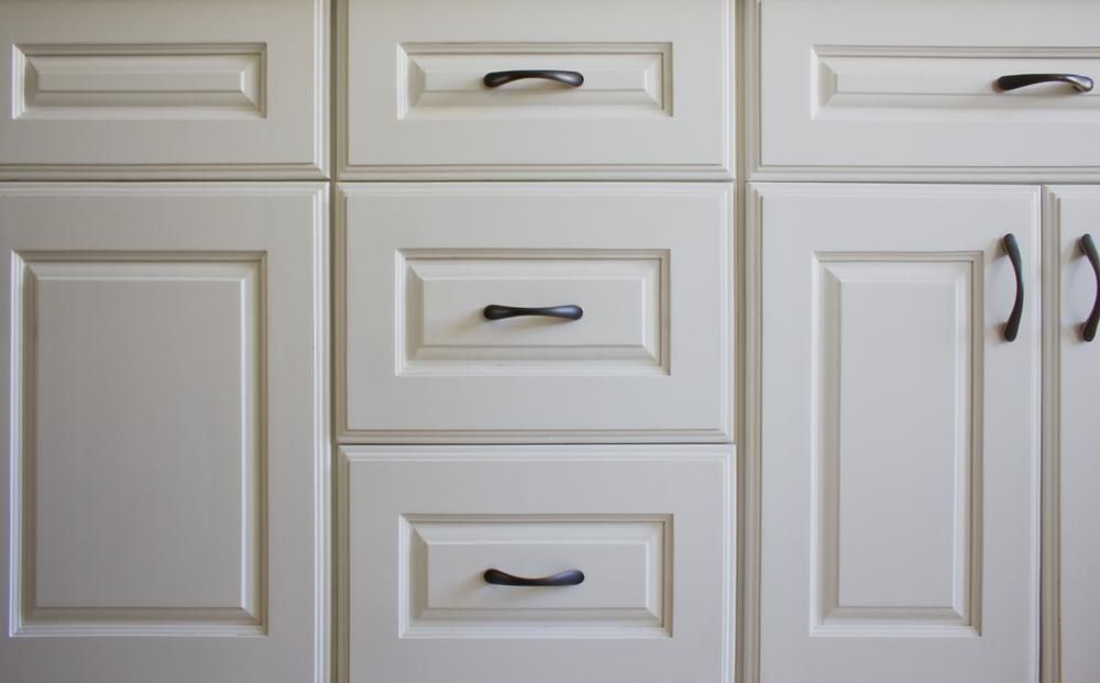 A close up of white cabinets with black handles