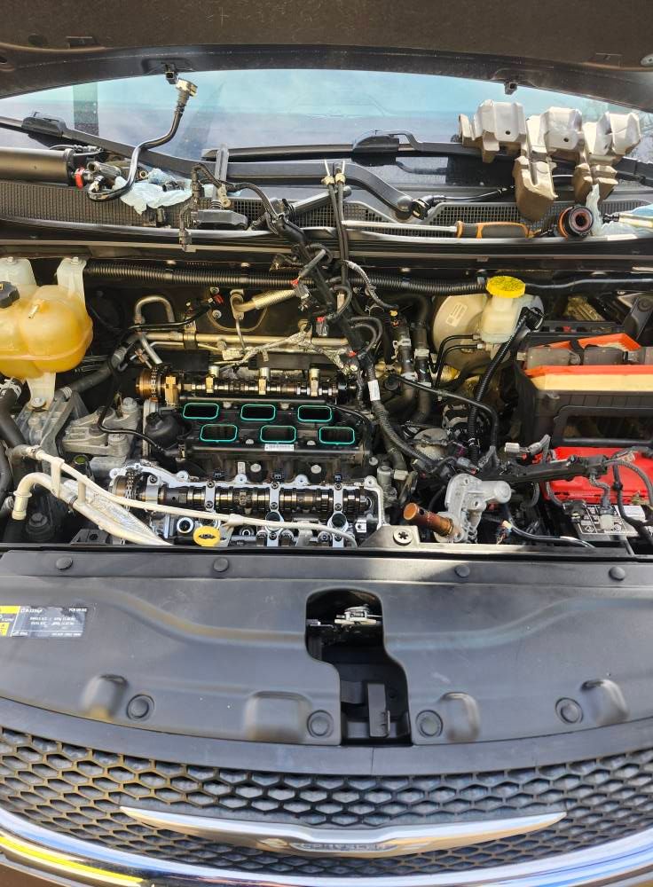 Open car hood showing engine bay with yellow coolant reservoir and exposed engine components