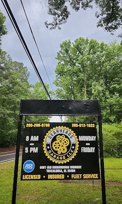 Black van with yellow graphics and business hours parked on a tree-lined street under power lines