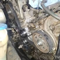 Close-up of a car engine with exposed timing belt and pulleys during repair