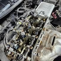 Close-up of a car engine with the valve cover removed, exposing camshafts and internal components.