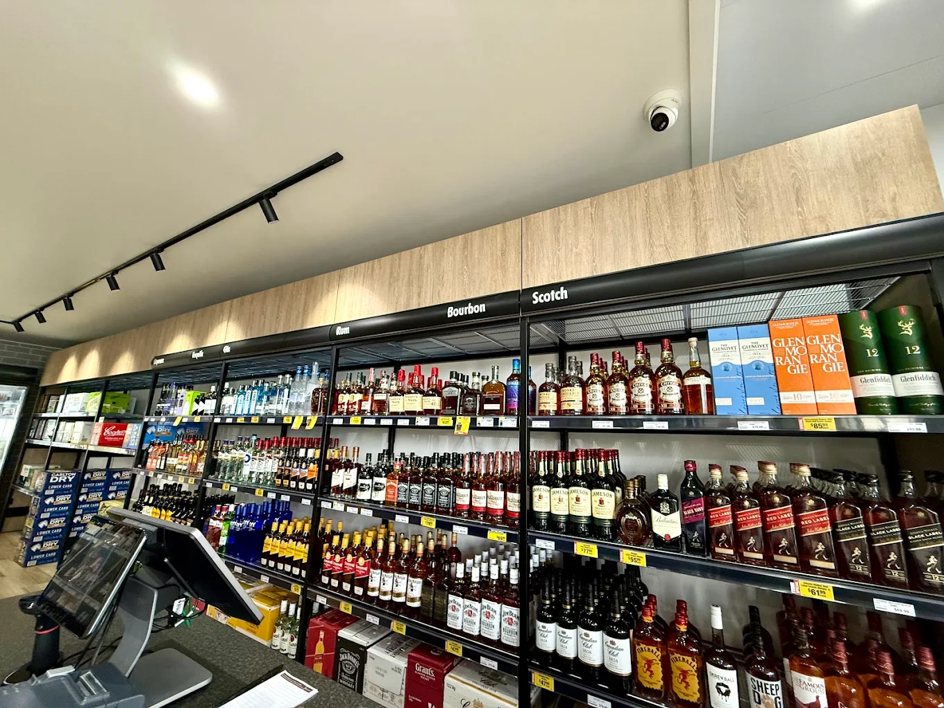 Supermarket beverage aisle with shelves of wine, beer, and drinks under ceiling lights