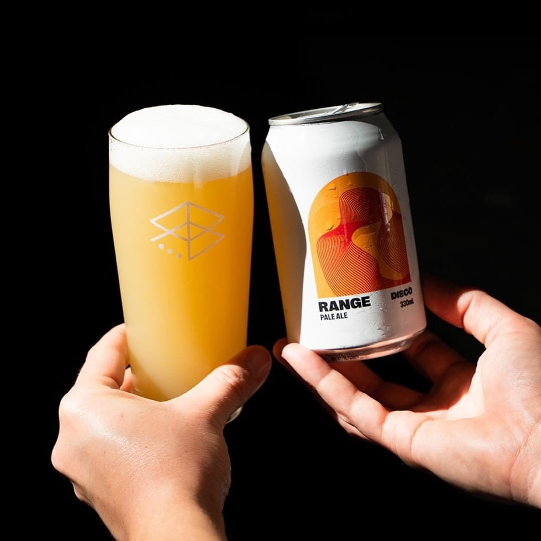 Person holding a beer glass and a can of 