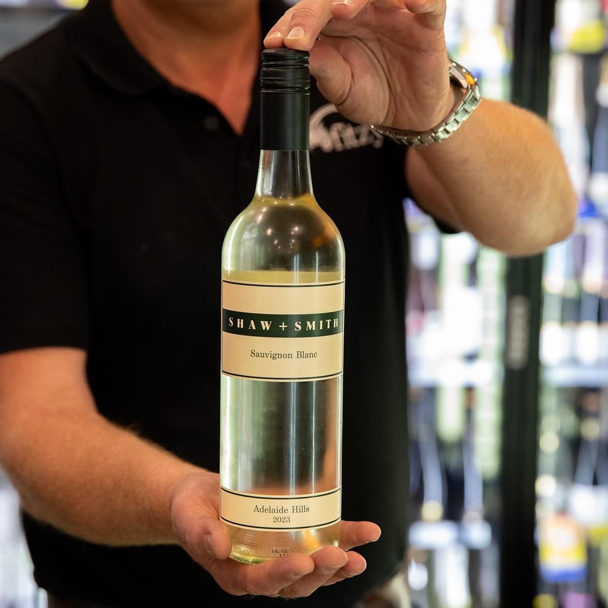 Person holding a bottle of Shaw & Smith Sauvignon Blanc wine.