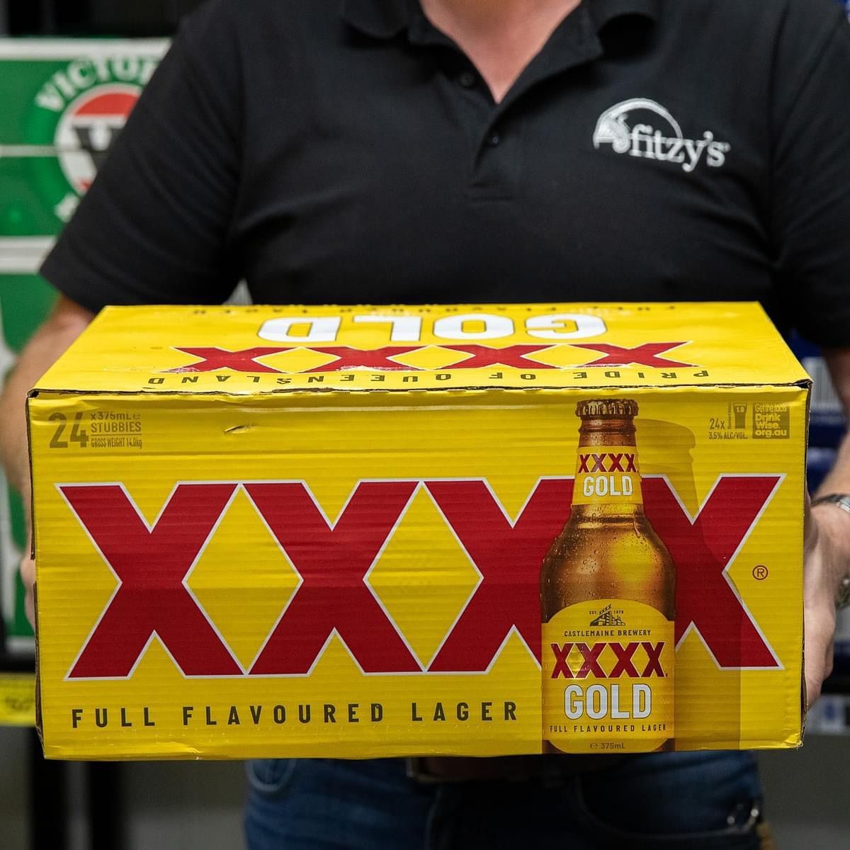 Person holding a yellow box of XXXX Gold beer; Queensland branding.