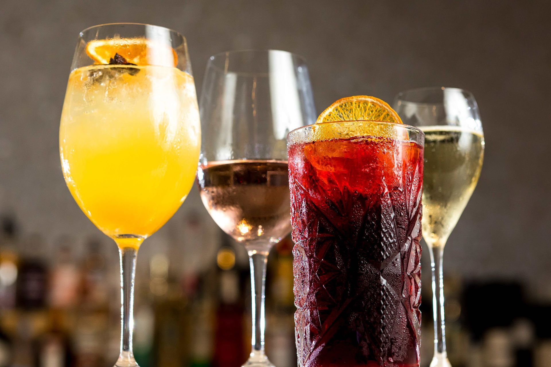 A row of wine glasses filled with different types of drinks.