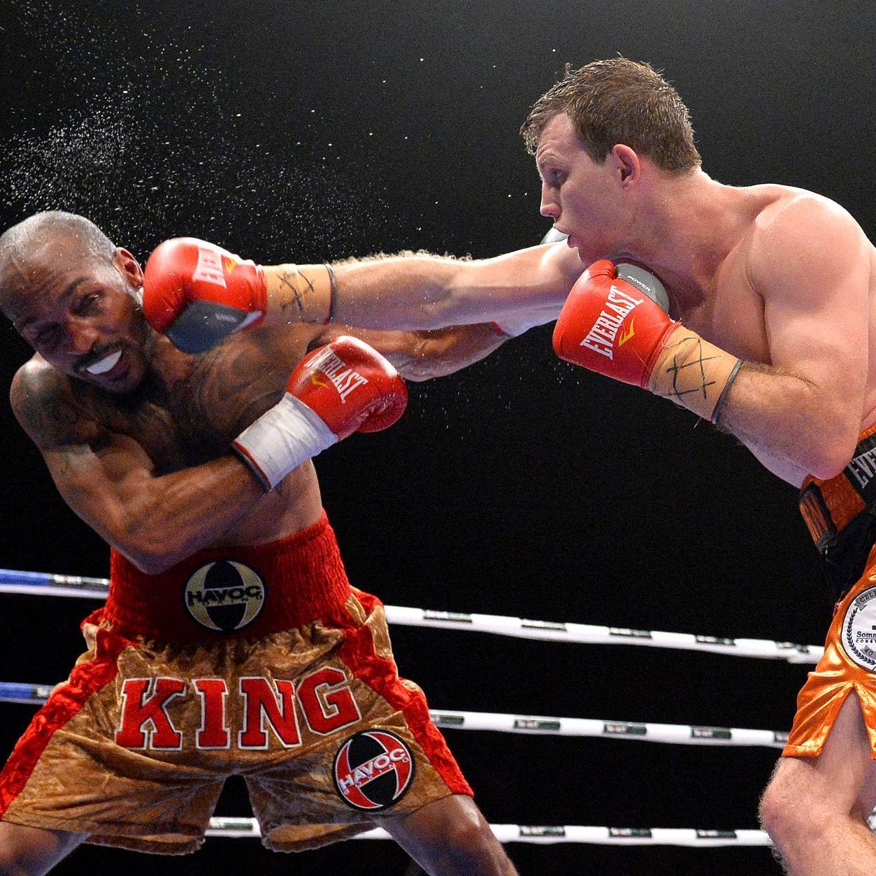 Two men are boxing in a ring and one of them is wearing shorts that say king