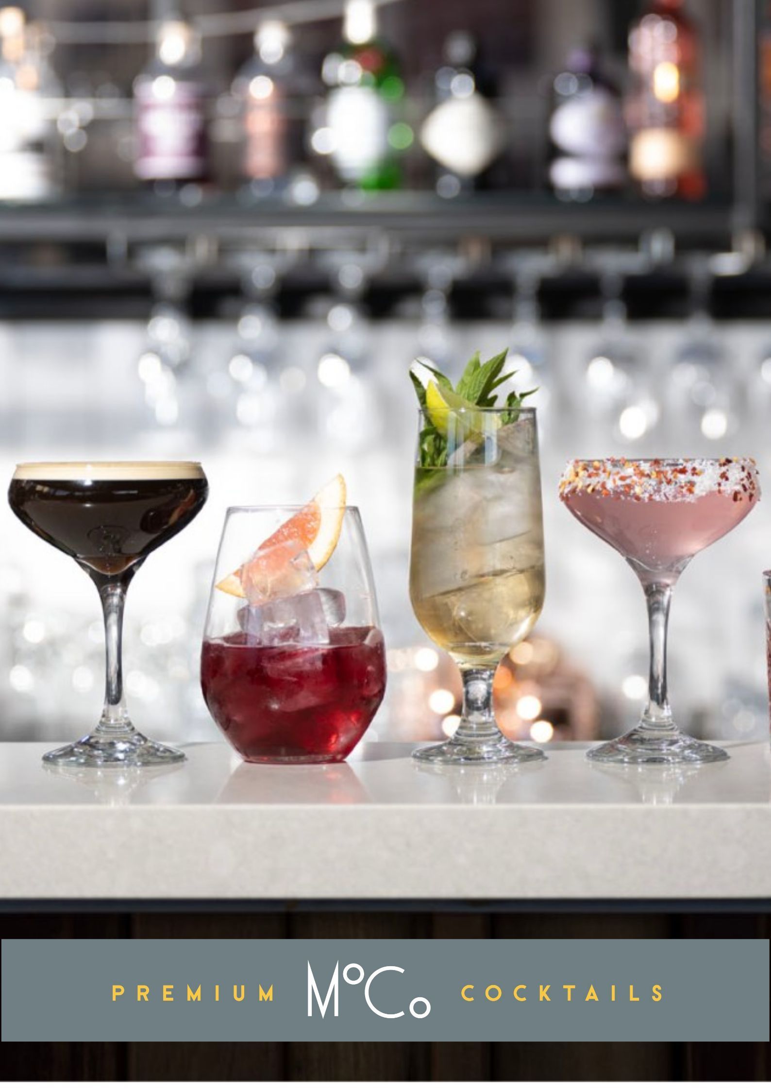 Four different types of cocktails are lined up on a bar counter.
