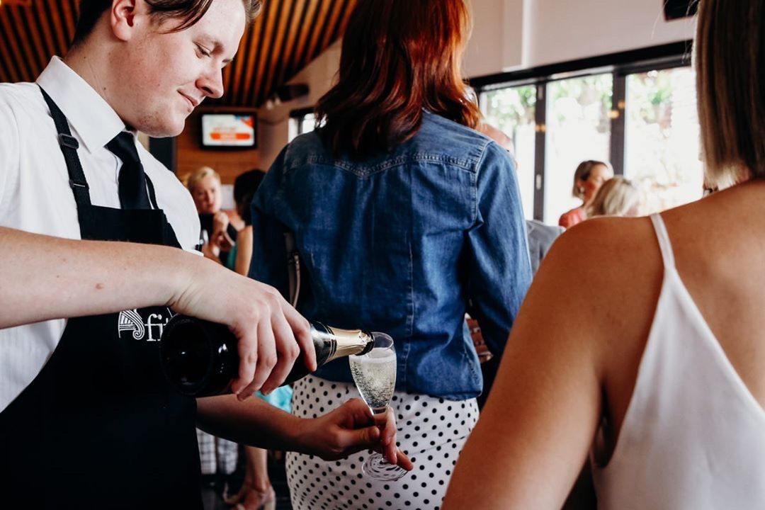 A man is pouring champagne into a glass for a woman.