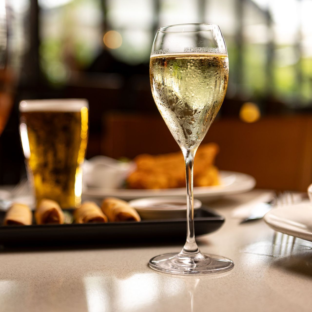 Champagne flute and beer glass on a restaurant table with bread and plates