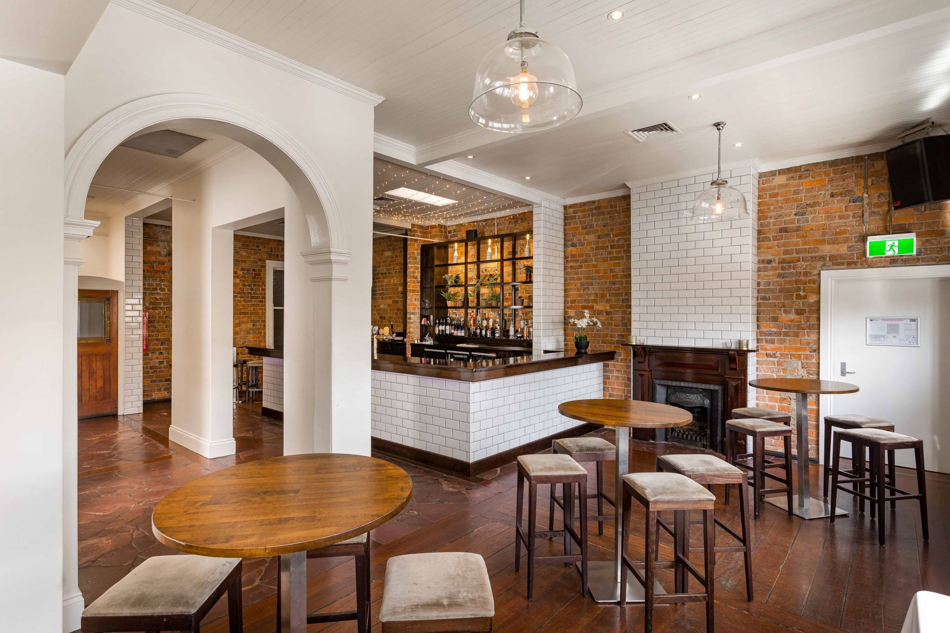 A large room with tables and stools and a bar in the background.