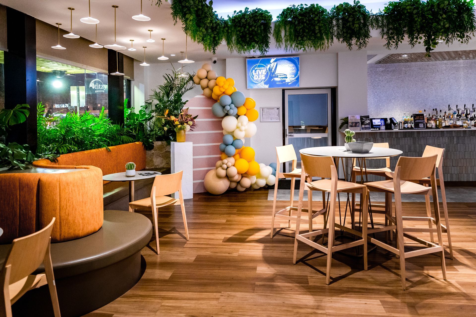 A restaurant with tables and chairs and balloons on the wall.