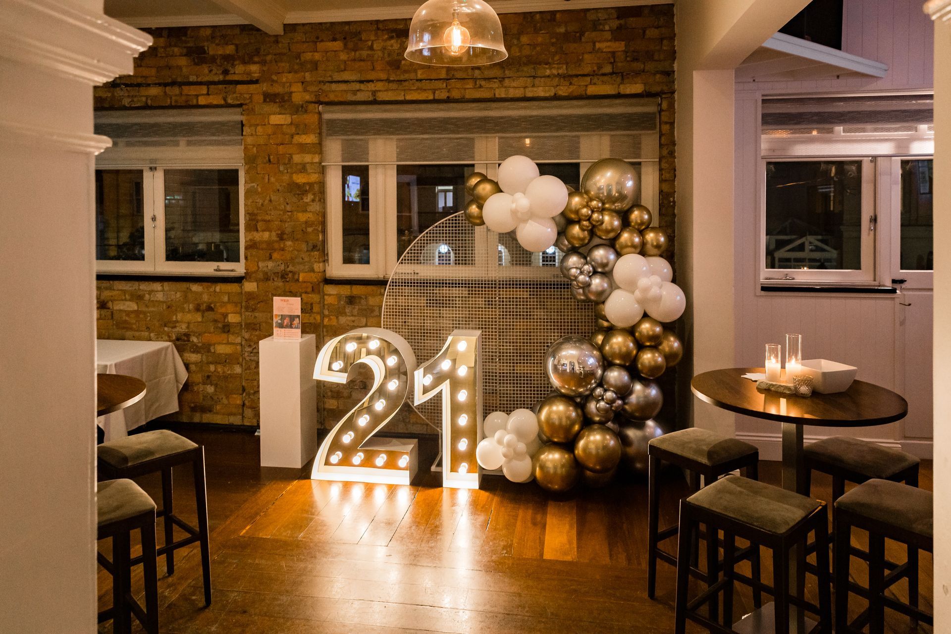 A room with tables and chairs and balloons in the shape of the number 21.