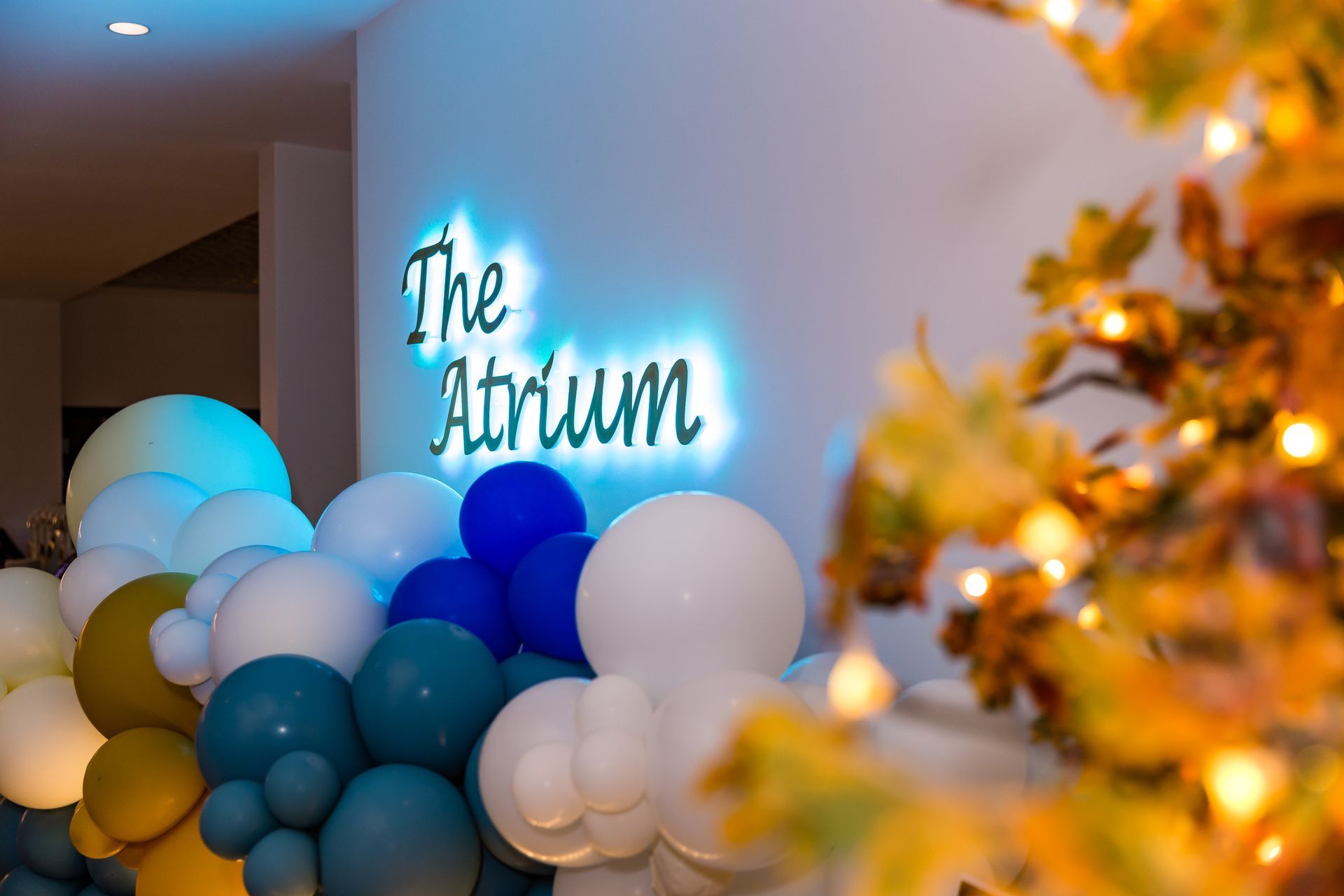 A bunch of balloons are sitting in front of a sign that says the atrium.
