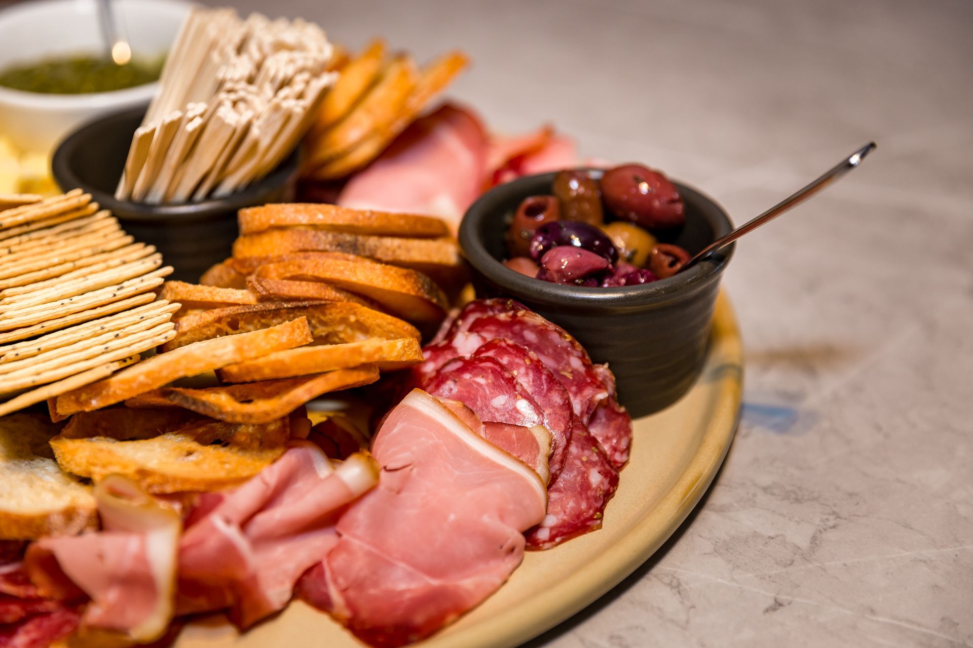 A plate of food with crackers and olives on a table.